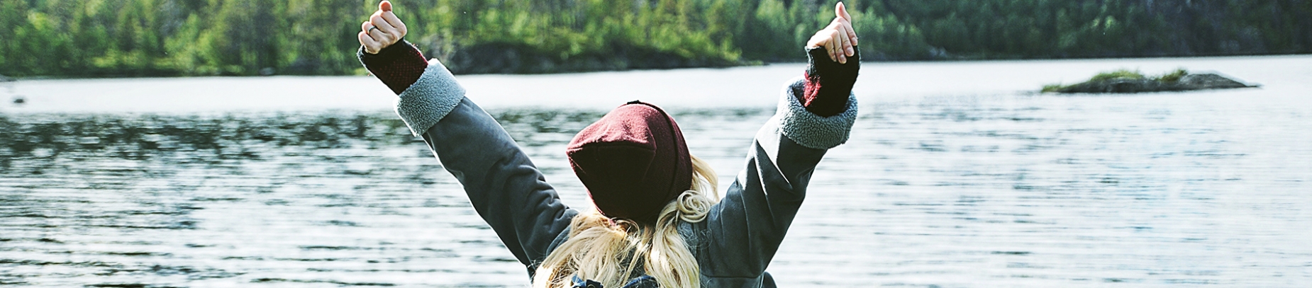 A women stretching her arms up while looking out over water