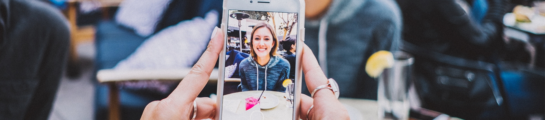 A women holding up a phone to take a photo of her friend A women holding up a phone to take a photo of her friend