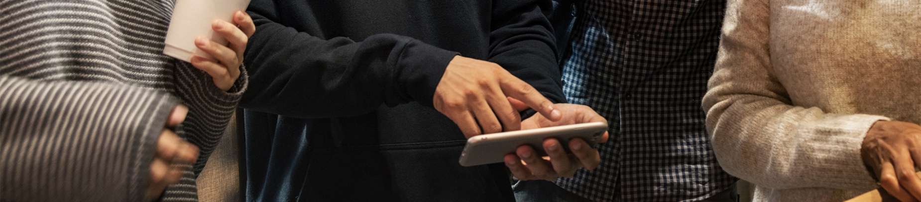 A guy looking at his phone and pointing to his friends A guy looking at his phone and pointing to his friends