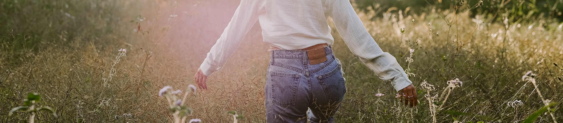 A women walking through a field with her arms out A women walking through a field with her arms out