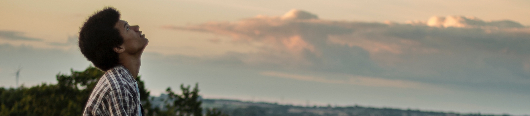 A man looking up to a sunset sky