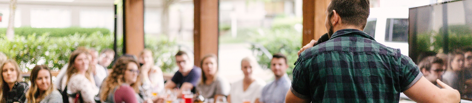 A man talking into a microphone to a crowd in a cafe A man talking into a microphone to a crowd in a cafe