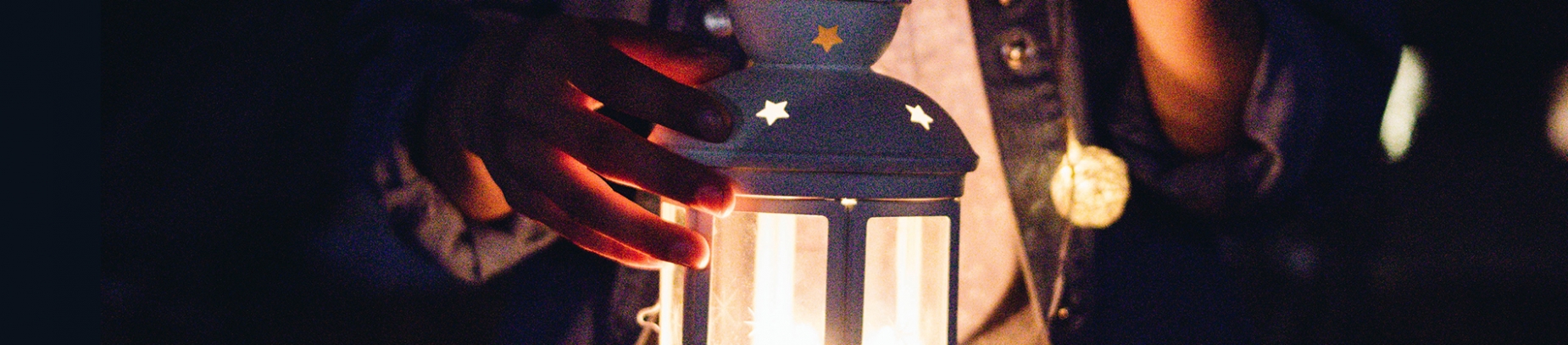 A women holding a lit lantern with stars on it A women holding a lit lantern with stars on it