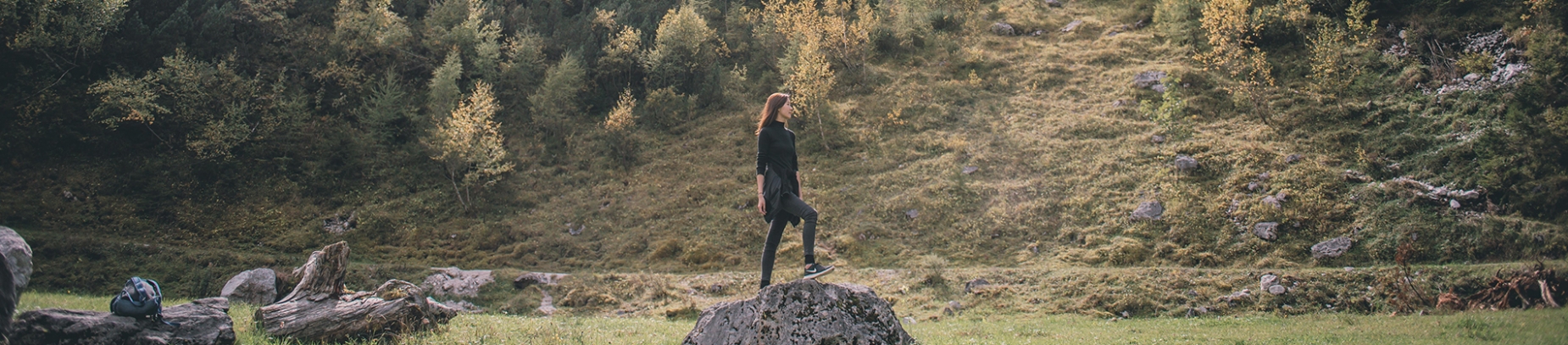 A women stood on top of a large rock in a field A women stood on top of a large rock in a field