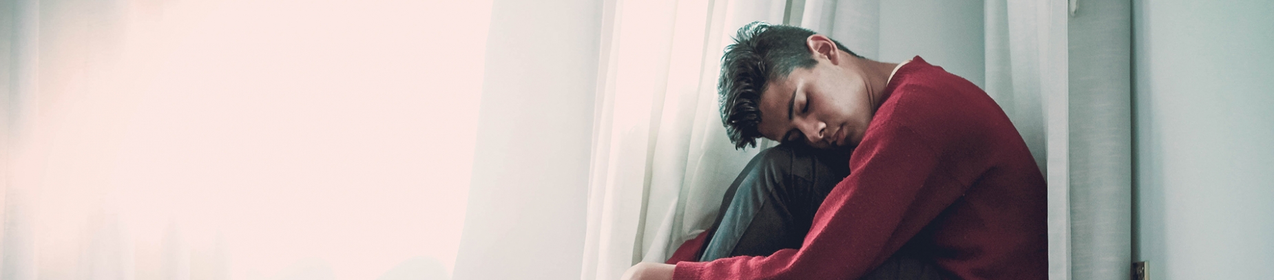 A man curled up in the corner of a room A man curled up in the corner of a room