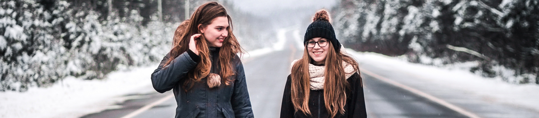 Two friends walking down a road in the snow together Two friends walking down a road in the snow together