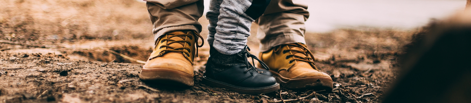 A father and young son stood in boots on a muddy path A father and young son stood in boots on a muddy path