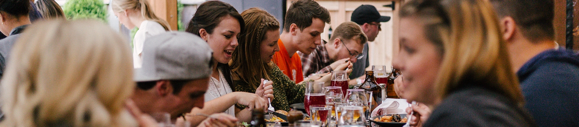 A group of people chatting and eating around a restaurant table A group of people chatting and eating around a restaurant table