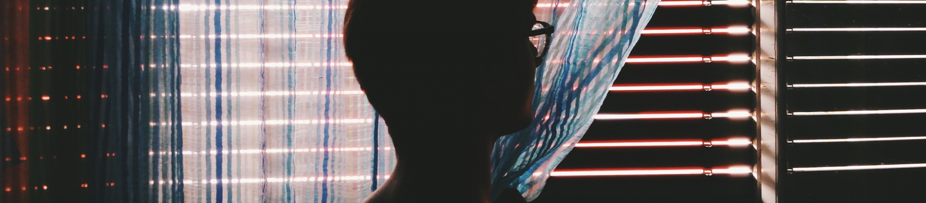 A man pulling curtains back to look out of the window A man pulling curtains back to look out of the window