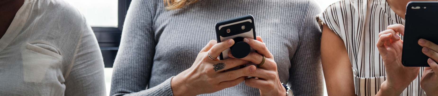Three women leaning against a window on their phones Three women leaning against a window on their phones