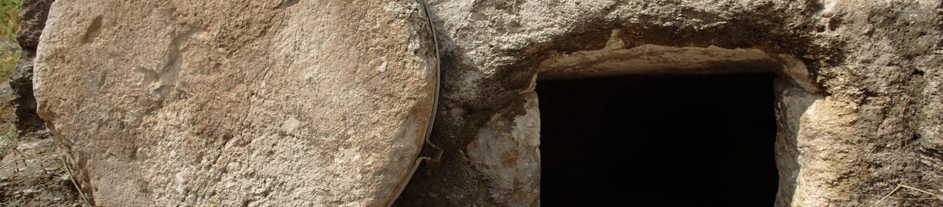 A open tomb with a large stone beside the entrance A open tomb with a large stone beside the entrance