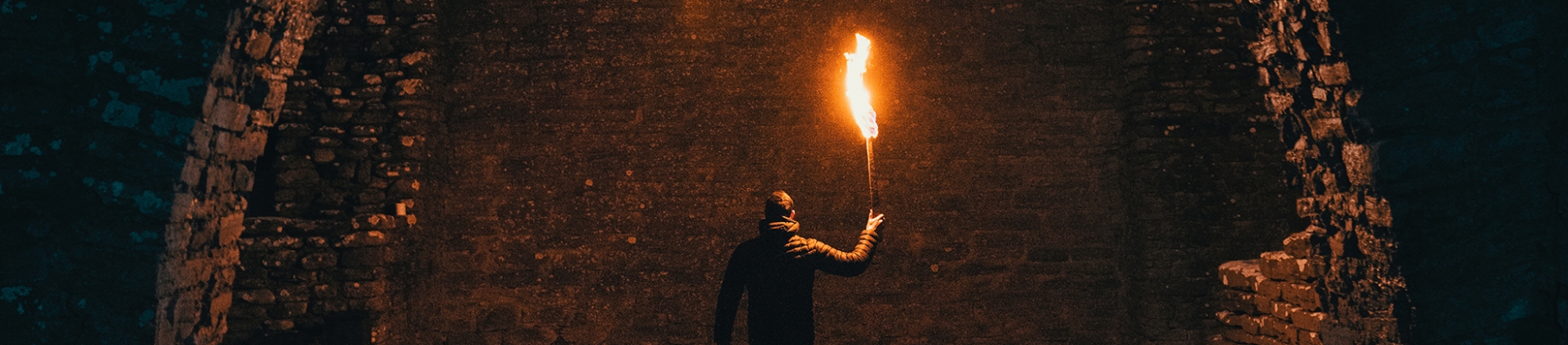 A man holding a flame up to a brick wall A man holding a flame up to a brick wall