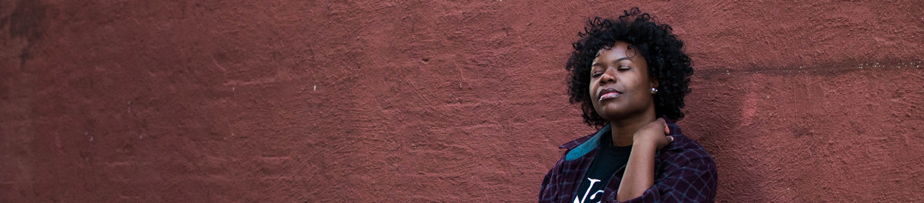 A women with her eyes closed leaning against a wall A women with her eyes closed leaning against a wall