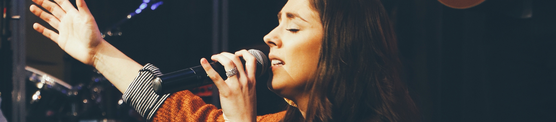 A women with her arm out singing in worship A women with her arm out singing in worship