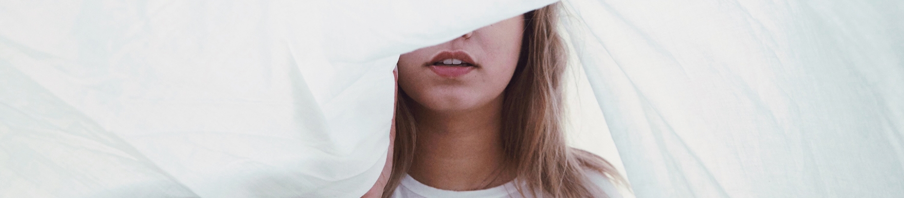 A women in a white top with a white sheet floating over her A women in a white top with a white sheet floating over her