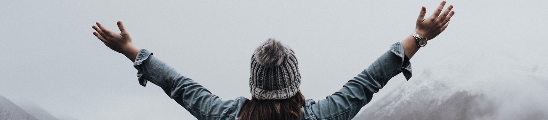 A women looking over mountains with her arms out wide A women looking over mountains with her arms out wide