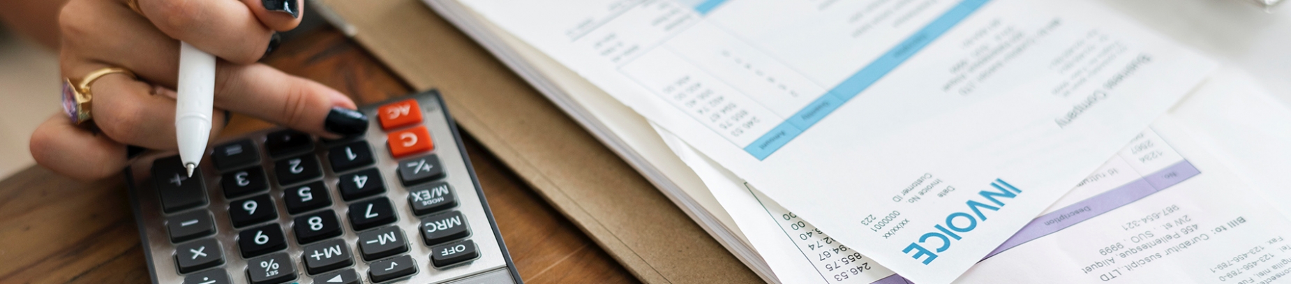 A women using a calculator to sort out invoices A women using a calculator to sort out invoices