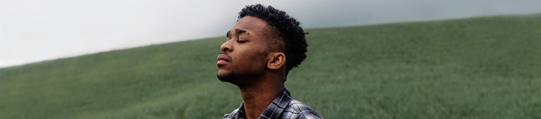 A guy stood in a field with his eyes closed in prayer A guy stood in a field with his eyes closed in prayer