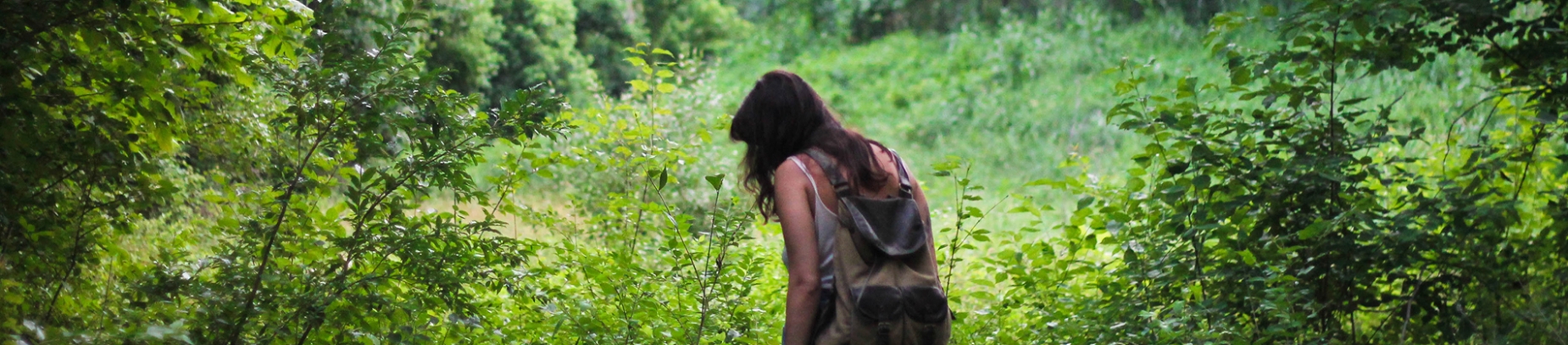 A women walking through a forest wearing a backpack