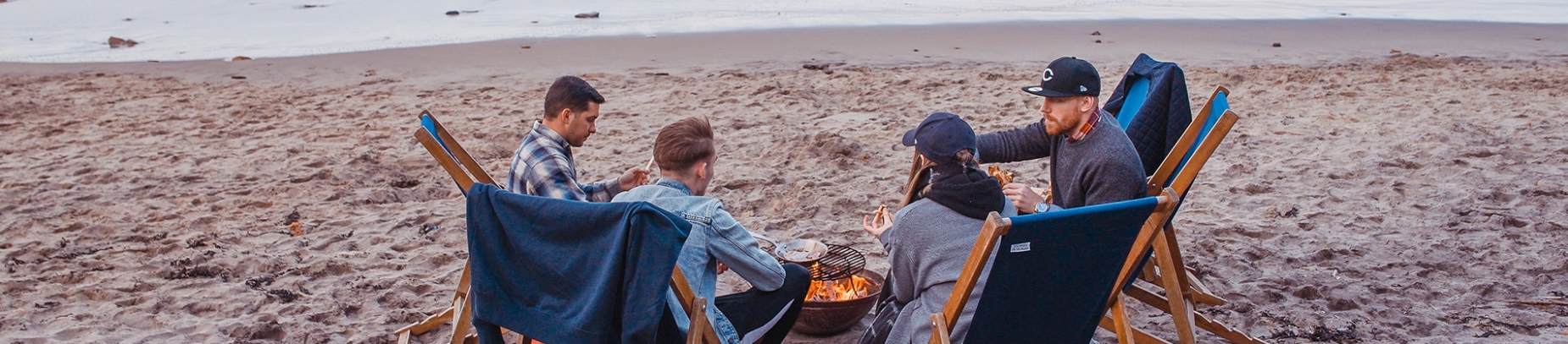 A group of friends sat on the beach around a campfire A group of friends sat on the beach around a campfire