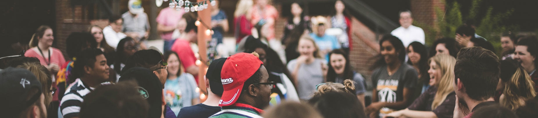A large group of people at a outside party, smiling and dancing