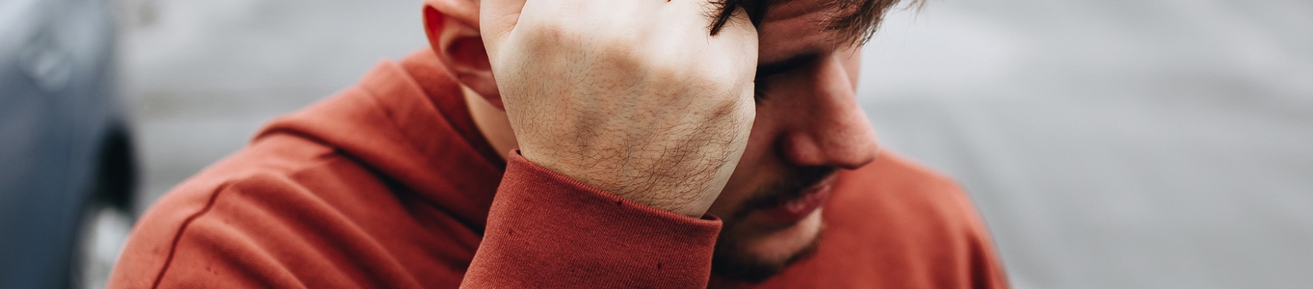 A guy in a red hoodie resting his head on his hand