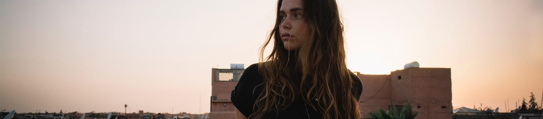 A women looking to the side with the sunset behind her A women looking to the side with the sunset behind her