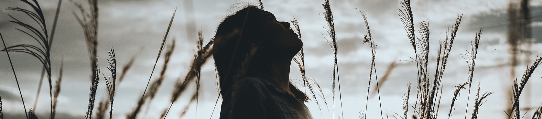 A women stood in a field looking up at the sky A women stood in a field looking up at the sky