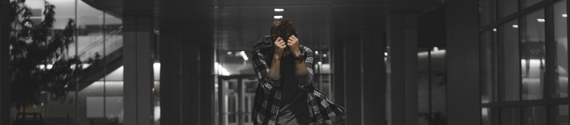 A man walking through a corridor with his hands up to his face A man walking through a corridor with his hands up to his face