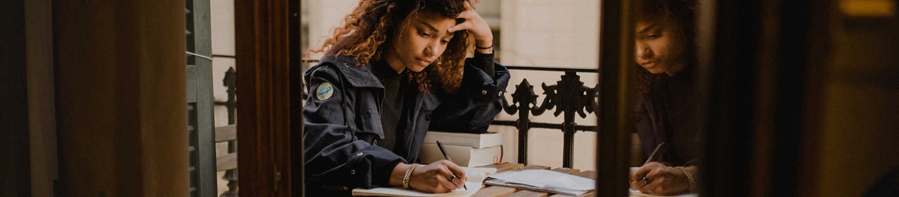 Women sat on her balcony writing and leaning on books Women sat on her balcony writing and leaning on books