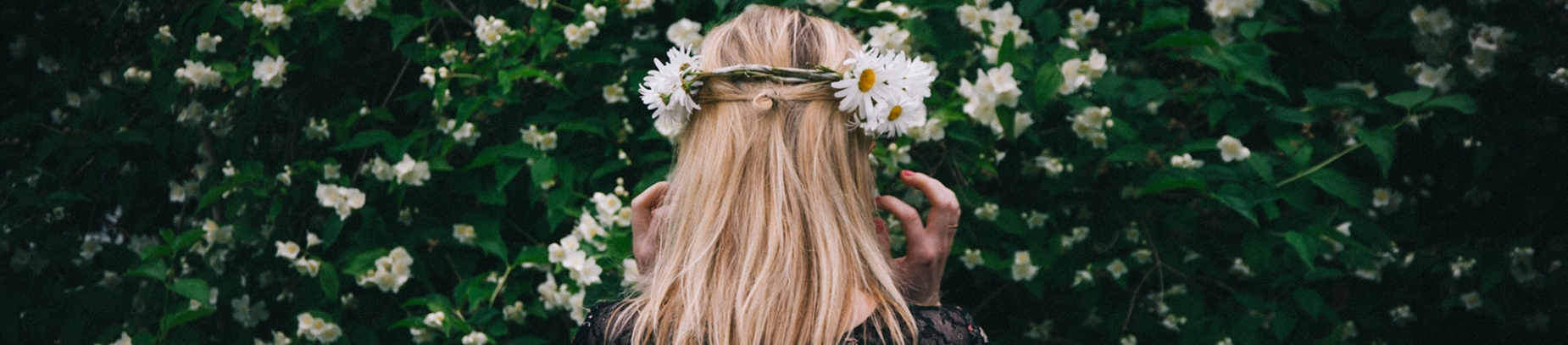 A women facing foliage wearing a flower crown A women facing foliage wearing a flower crown