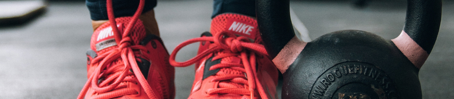 Red running trainers next to a gym weight