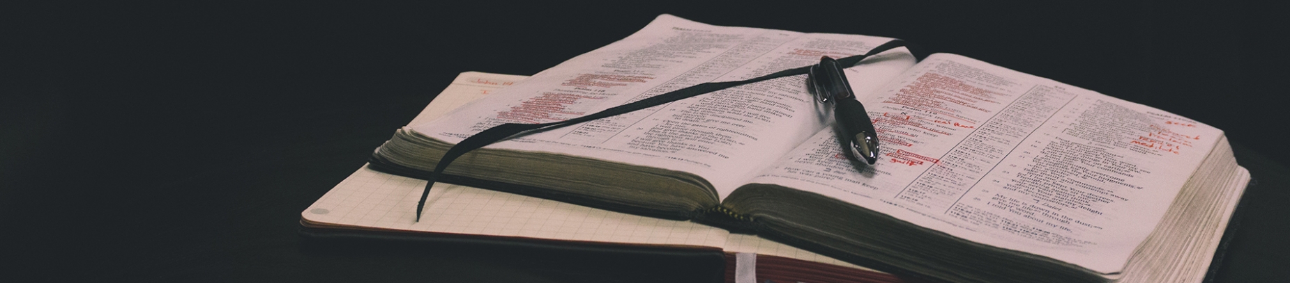 A open bible with a notebook and pen A open bible with a notebook and pen