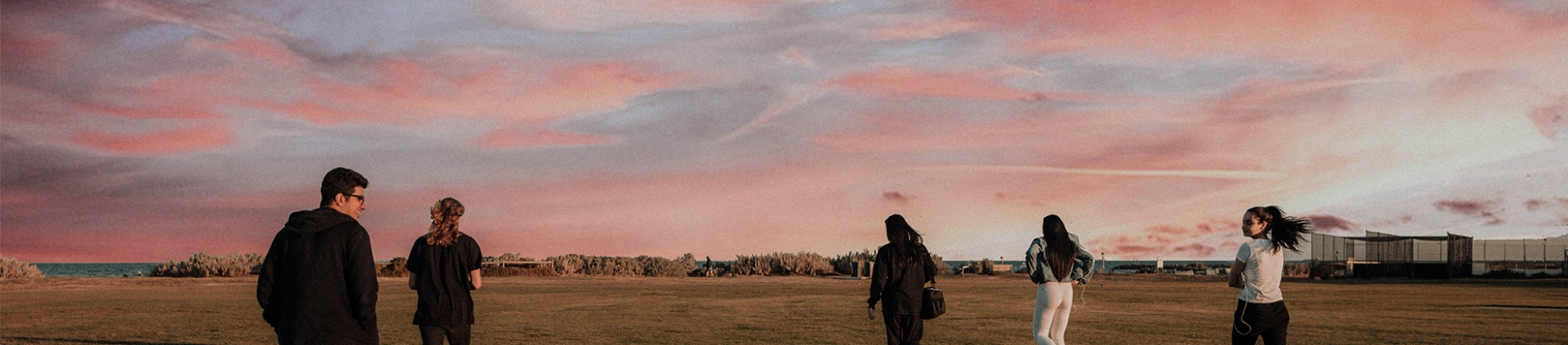 A group of friends walking through a playing field at sunset A group of friends walking through a playing field at sunset