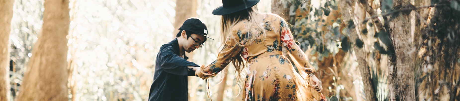 A man and women in a forest. The man is helping the women down off a log A man and women in a forest. The man is helping the women down off a log